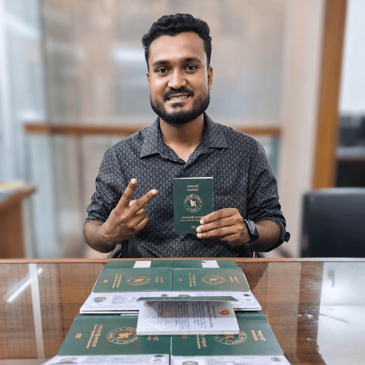 CV Felow client holding an approved passport, with a set of processed passports and documents on the desk in front of him